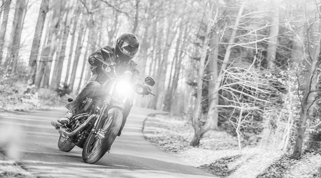 Young man riding chopper on road in forest